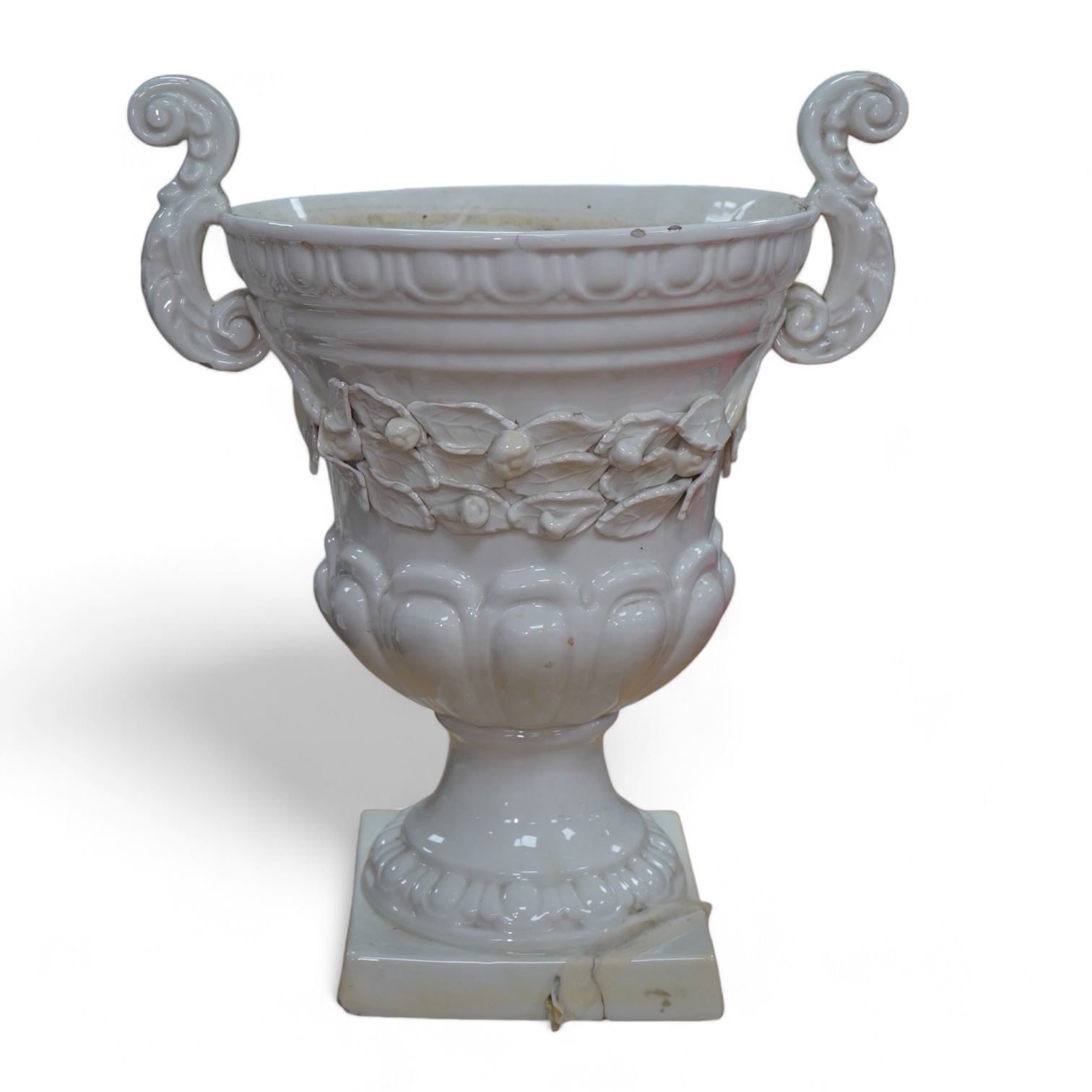 A large cream glazed pottery pedestal vase, with decorative swag of fruit and leaves, 43cm high. Condition - corner of square base broken, glazing chipped on top rim and fruit and leaf decoration broken